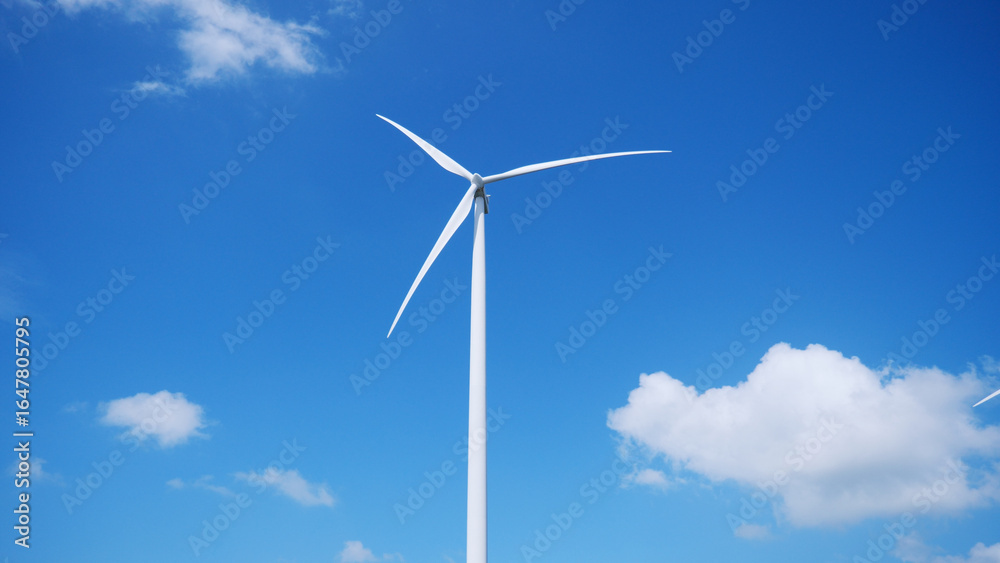 Wind Turbine in Blue Sky: A solitary wind turbine gracefully turning in the vibrant blue sky, generating clean energy, representing sustainability, and eco-friendly practice. Wind Turbine in Blue Sky: A solitary wind turbine gracefully turning in the vibrant blue sky, generating clean energy, representing sustainability, and eco-friendly practice.