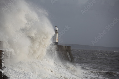 Murais de parede Giant waves hitting the sea wall and lighthouse at Porthcawl.
