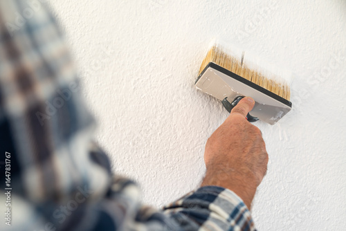 Close-up of a hand. A painter paints a masonry wall with white paint using using the paintbrush. Construction industry. 