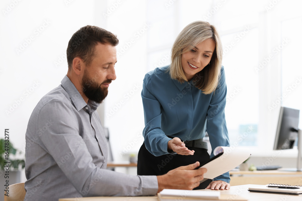 Fototapeta premium Smiling business partners working with documents at table in office