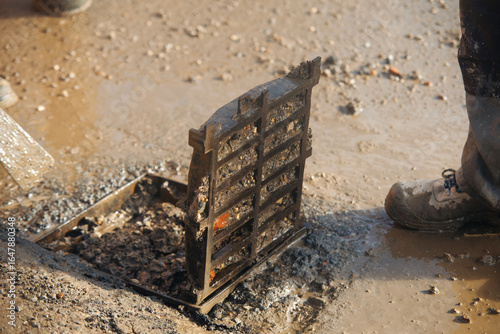 Road workers opened road gully iron top to clean it from debris and dirt to prevent street flooding