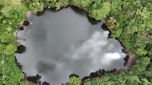 Aerial of circular crater lake inside dense rainforest