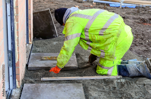 Fotografie Paving works in progress as builder laying concrete paving slabs for new footpat