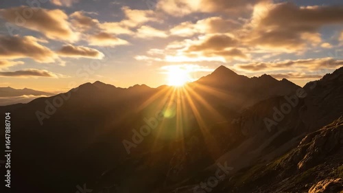 Sunrise Over Mountain Peaks in Timelapse - The video captures the sun rising above rugged mountain peaks, casting a warm glow across the landscape.