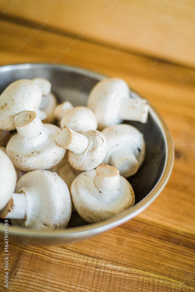 Fresh white mushrooms in a metal bowl on wooden background. Fresh white mushrooms in a metal bowl on wooden background.