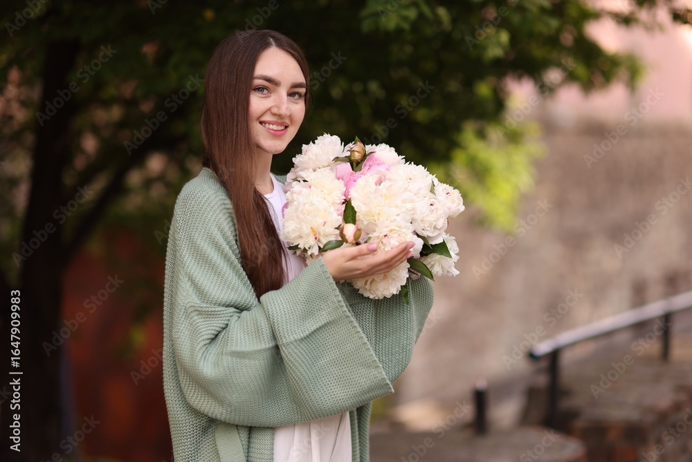 Fototapeta premium Charming woman with bouquet of beautiful peonies on city street