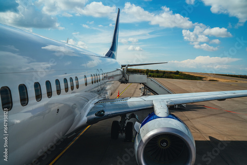 Airplane at an airport, ready for takeoff, with modern terminals, runways, and aviation activity in the background.