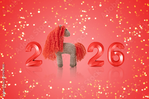 Fotografie Crocheted toy fiery red horse and gold numbers