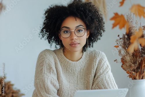 Woman Working on Laptop Indoors With Autumn Decorations and Cozy Sweater.