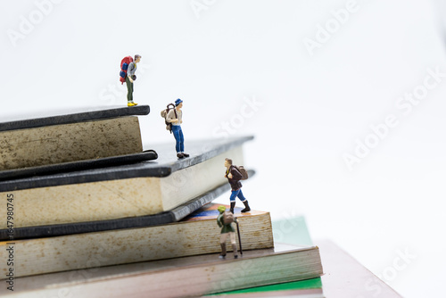 Travelling and Education concepts. Group of miniature people mini figures with backpack 
 walking and climbing on a mountain of textbooks