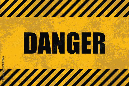 A striking hazard sign is displayed against a textured yellow background. The word "DANGER" is prominently featured between warning stripes. This indicates a potentially hazardous area.