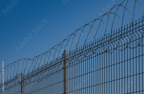 Razor wire. Metal wire fence. Blue sky background.