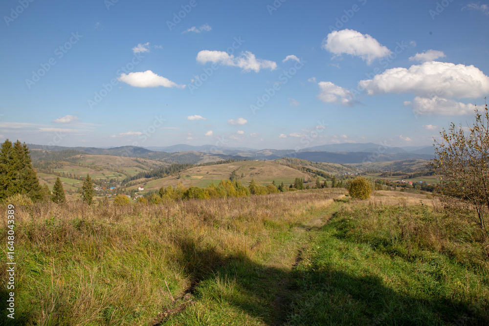 Obraz premium This beautiful landscape showcases a vast field of hills under a clear blue sky with clouds.