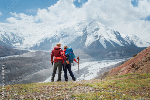 Foto Backpackers couple with backpacks hugging enjoying Pamir mountains during Lenin peak ascent with mountain peaks in background