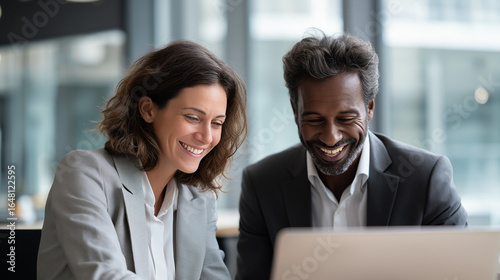 Smiling multicultural business partners discussing project strategy on a laptop