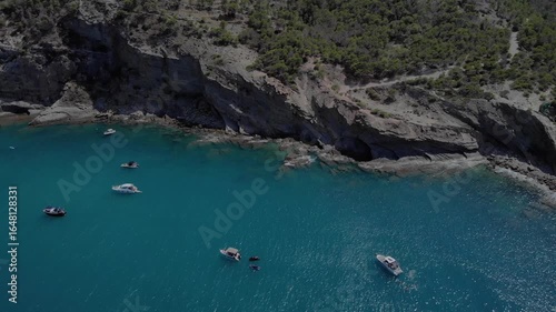 Multiple boats floating peacefully along coastal shoreline in Spain