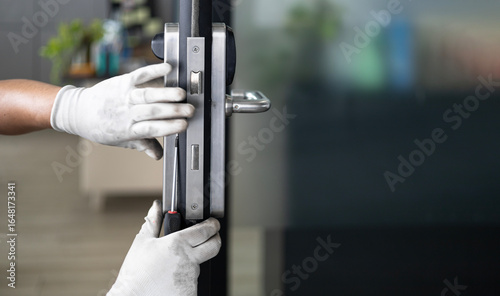 man repairs the door. repair, installation and adjustment of locks and handles on the entrance