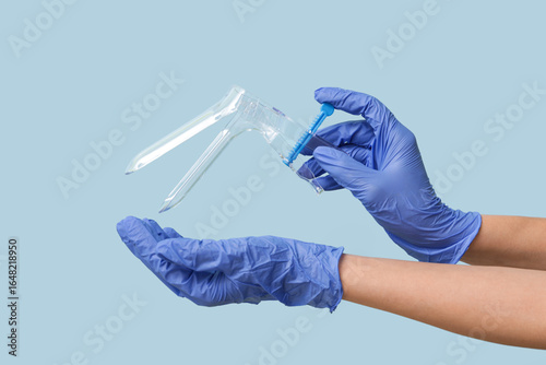 Photos Doctor hands in medical gloves with gynecological speculum on blue background