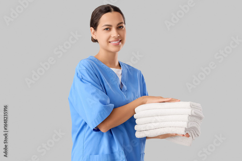 Female massage therapist with clean towels on light background