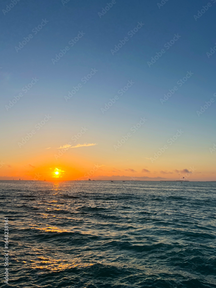 Fototapeta premium Orange Sun Setting Over Rippling Ocean