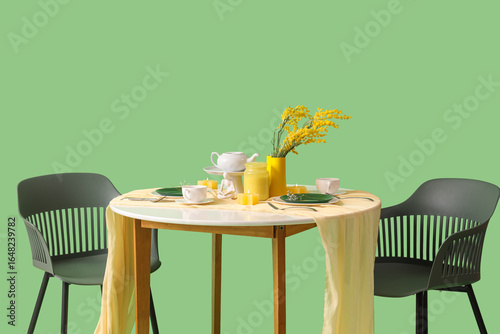 Served restaurant table with flowers on green background