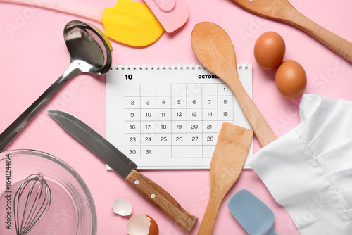 Calendar with chef's hat, kitchen utensils and eggs on pink background