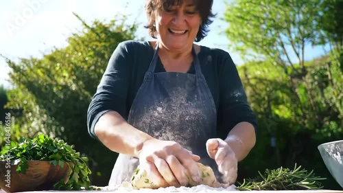Elderly Woman Kneading Dough Outdoors in Sunlit Garden with Flour Dusting Hands