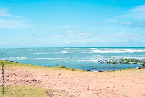 Serene beach scene with gentle waves, clear blue sky, and sandy shore