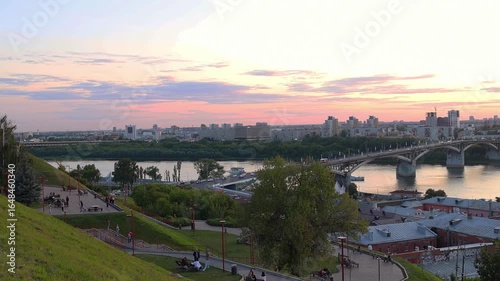 Scenic sunset over the Volga River in Nizhny Novgorod, Russia, with historic buildings, bridge and moored boats, creating a peaceful golden-hour cityscape. Beautiful cityscape view from top.