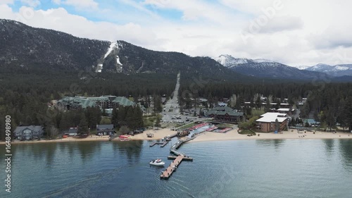 Riva Grill and Marina with sunshine and snow storm arriving over South Lake Tahoe looking toward Heavenly Valley on a cold May day with freezing rain Drone footage