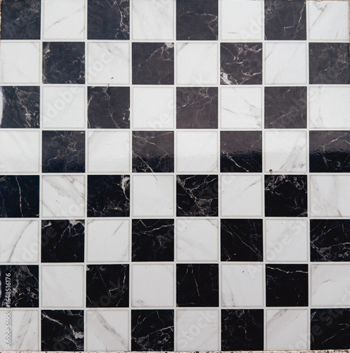 Black and white marble checkered floor tiles in a geometric pattern, creating a classic and elegant background, suitable for architecture, design, and decorative concepts.