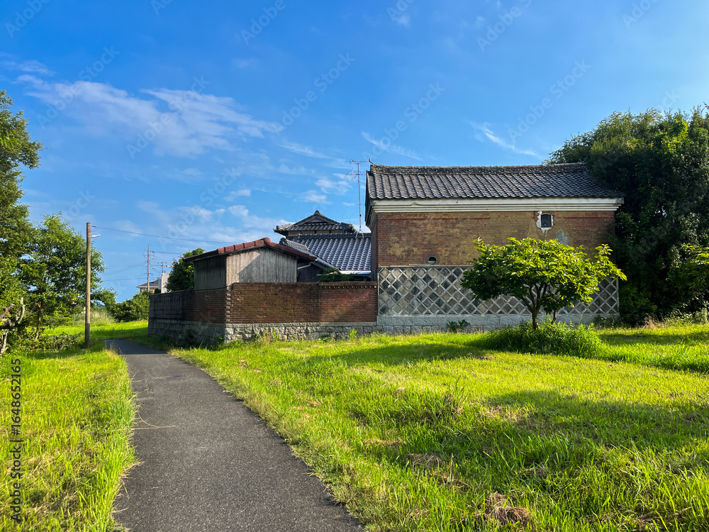 青空と草原に囲まれた日本の伝統的な蔵と田舎道の風景 青空と草原に囲まれた日本の伝統的な蔵と田舎道の風景
