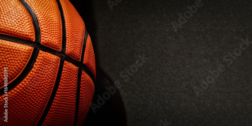 A close-up view of a basketball showcases its textured surface and black seams, providing a dynamic sports image. Banner with copy space for text