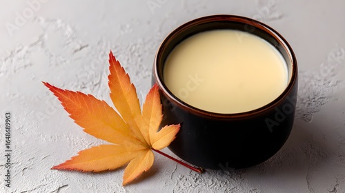 Creamy drink in a dark bowl with an autumn leaf.