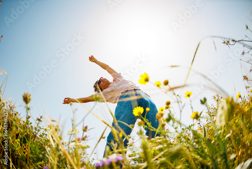 young and cheerful guy dances among the flowers. Handsome man dancing in nature. Summer mood. Happy young guy among blooming flowers, outdoors.
