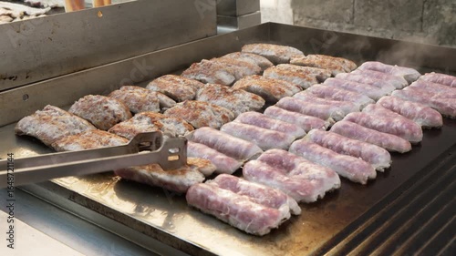 hand turning sausages on the grill
