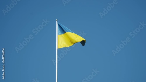 Ukrainian flag waving in the wind on a pole in the blue sky