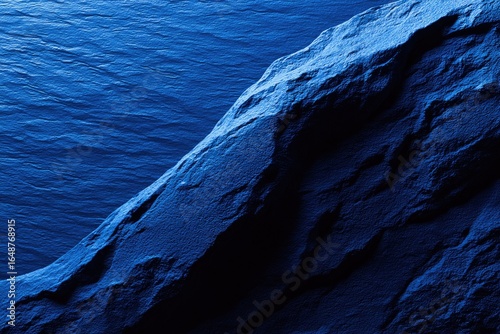Deep blue rock face meets a vast expanse of ocean