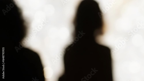 Blurred silhouette of two people against a bokeh light background.
