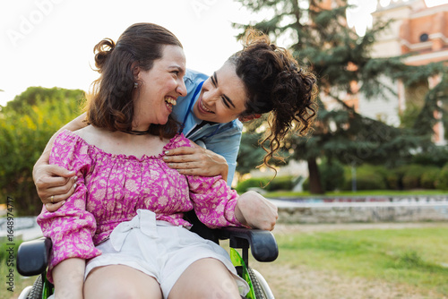 Happy nurse with arm around woman sitting on wheelchair