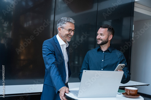Business manager and colleague discuss work together in modern office