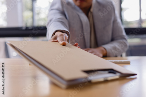 businessman handing over a brown folder across the desk, concept for document delivery, business agreement, contract signing professional office communication.