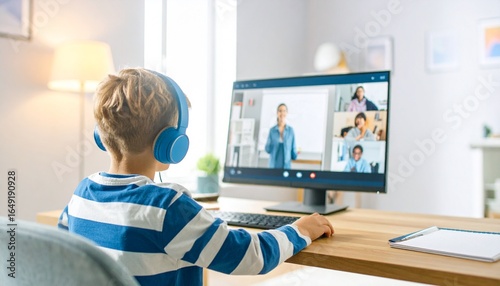 Young boy learning online with teacher and students during video call in modern bright room