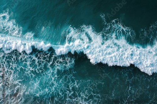 Aerial view of crashing waves. Dark teal ocean water with frothy white crests of waves breaking