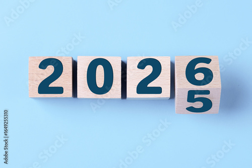 2026 Happy New Year. Wooden cube block change from 2025 to 2026 on blue. Concept 2026 New Year background. Business, resolutions, goals, inspiration, success, ideas