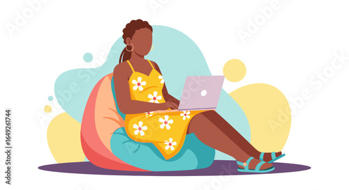 A young woman relaxes comfortably on a beanbag chair while working on her laptop, enjoying a casual work environment.