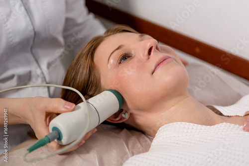 Foto Non-invasive facial lifting: woman undergoing microcurrent therapy for firmer sk