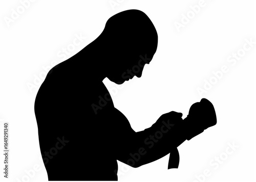 Silhouette of a boxer wrapping his hands with boxing wraps in preparation for a fight or training session