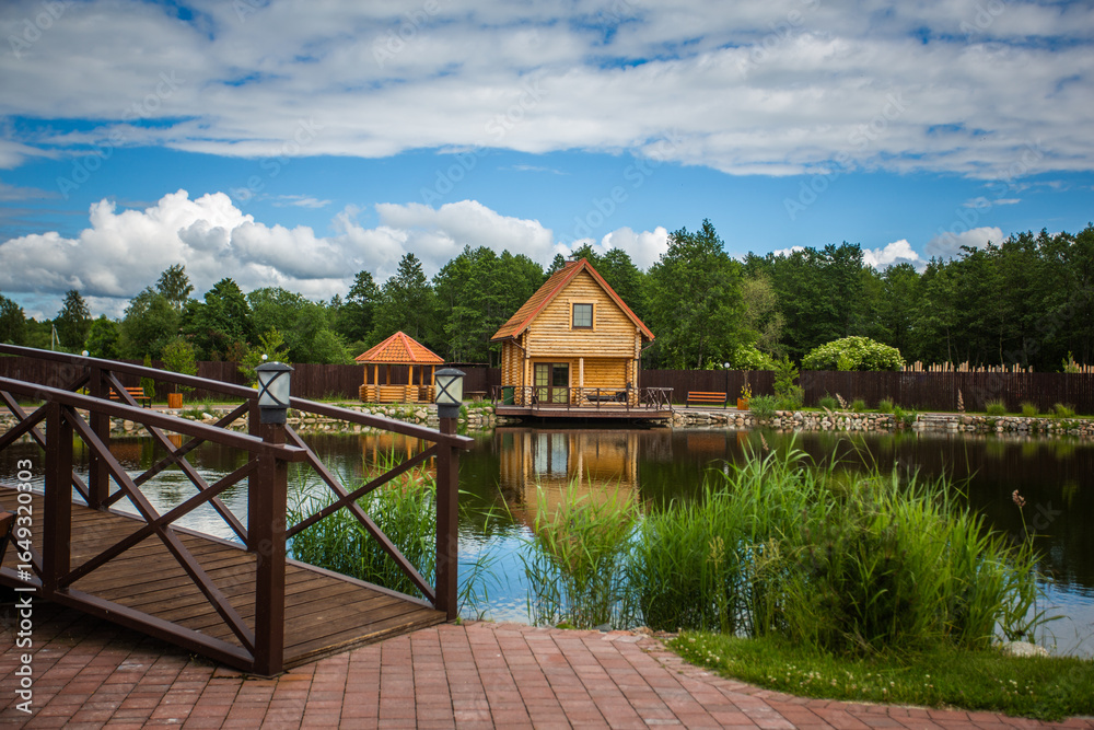 Fototapeta premium A wooden bridge over a pond with a house in the background