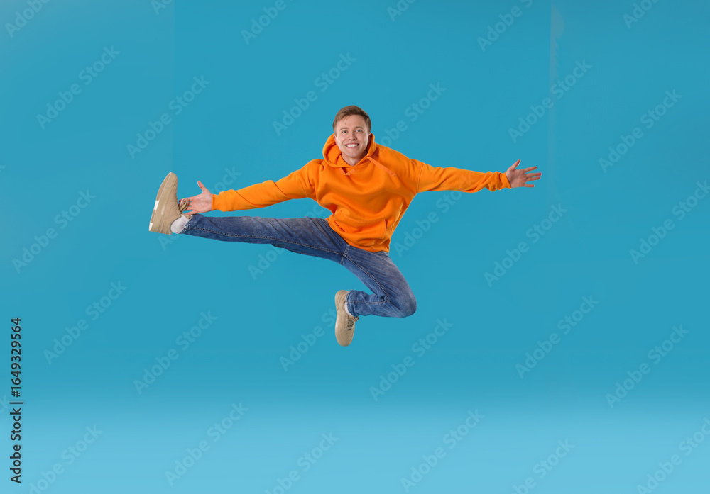 Obraz premium Happy young man jumping on light blue background
